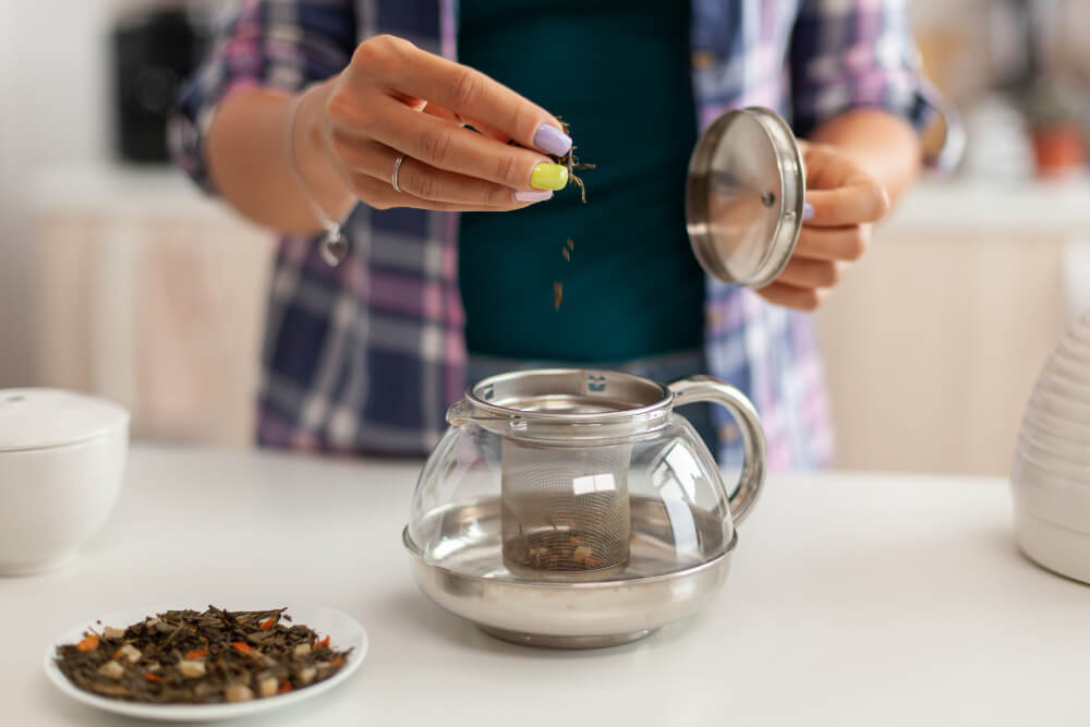 A woman carefully placing various herbal ingredients into a glass jar, skillfully crafting a medicinal blend. The image showcases her hands arranging colorful herbs and spices with precision, creating a visually appealing composition. This herbal concoction reflects. Similar to toxic substances, anger in the Quran can be viewed as a harmful element that, when processed through the antidote of forgiveness, transforms into a healing balm – much like the medicinal properties found in this herbal concoction."