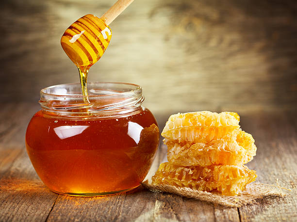 A jar of golden honey with a honeycomb on a rustic wooden table, reflecting the essence of 'shifa' (healing) in the Quran.