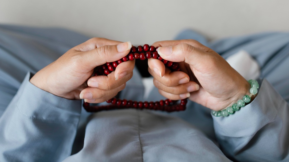 A woman with tasbih beads on her hand, immersed in prayer, reflecting on the profound connection of the human heart in the Quran.